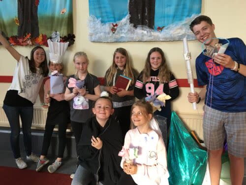 Children and youth group members smiling and holding craft projects at church.
